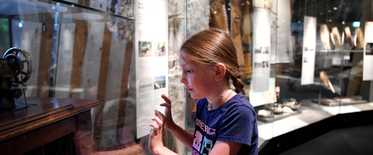 A young girl looks through glass at an artifact in the Human History Hall.