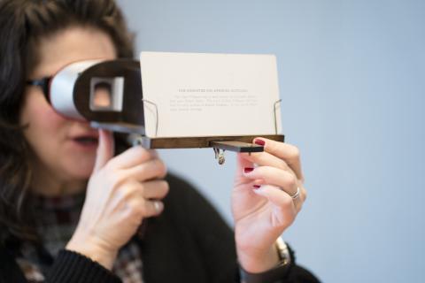 A Museum patron peers through an antique stereoscope.