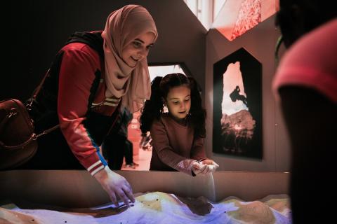 A woman in a hijab smiles as she plays with her daughter at an activity table in the Royal Alberta Museum Children's Gallery..