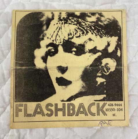 A photo of a vintage paper flyer for a club called Flashback. The Flyer has a black and white photocopy style portrait of a flapper woman. The word "Flashback" is under the image.