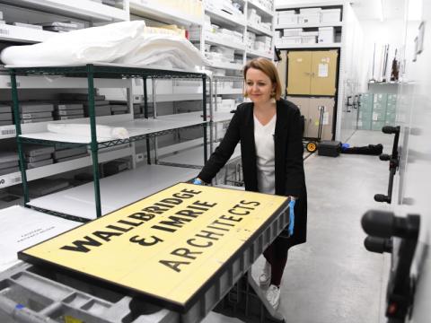 A curator displays a sign that says "Wallbridge & Imrie Architects"