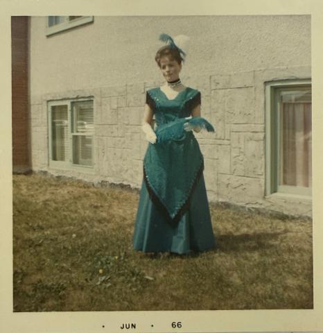 Simone Bessette in the Ginger Rogers inspired dress she created in 1966. The dress is full length and dark green with black fringe accents. 