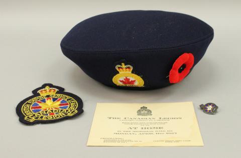 A Royal Canadian Legion crest, hat, pin and certificate. The hat is a dark navy colour adorned with a legion crest and poppy.