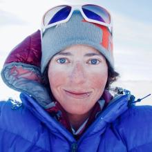 Headshot of Dr. Alison Criscitiello. She is wearing a blue winter coat and knit cap. She has sunglasses on top of her hat. She is looking into the camera with a smile on her face.